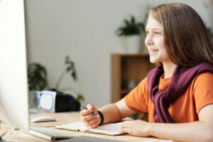 A woman staring on her computer screen while writing